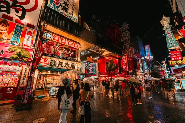 Rua de Shinsekai, em Osaka, com pedestres e letreiros luminosos à noite