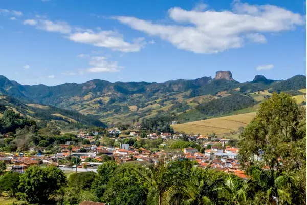 Vista panorâmica de São Bento do Sapucaí com casas, áreas verdes e montanhas da Mantiqueira ao fundo.