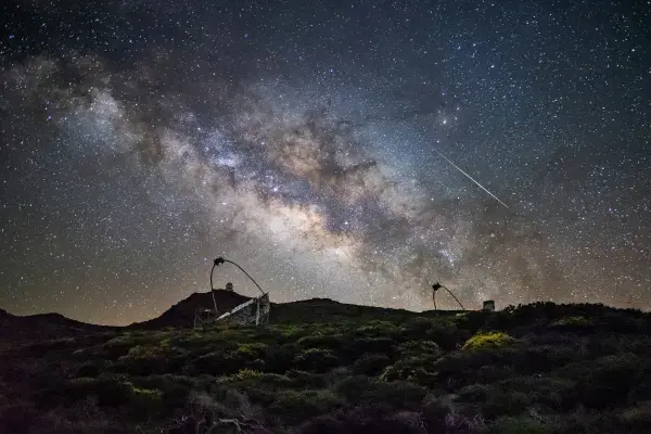 Via Láctea sobre telescópios e vegetação rasteira em La Palma, Ilhas Canárias