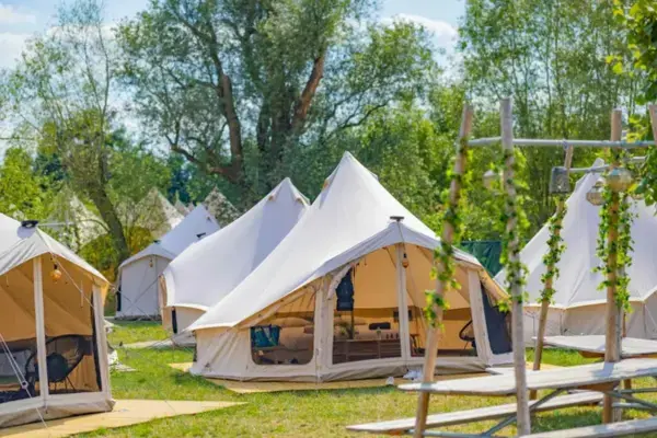 Tendas confortáveis do acampamento DreamVille no Tomorrowland Bélgica entre árvores e área verde