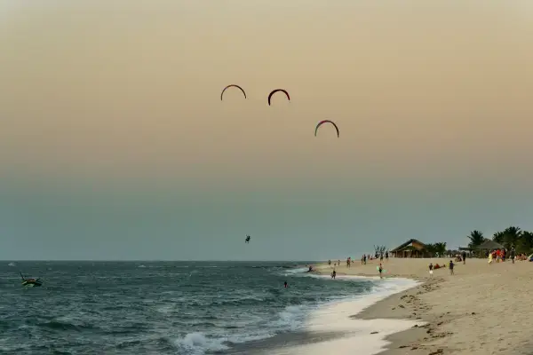 Praia extensa em Barra Grande no Piauí ao entardecer, com praticantes de kitesurf no céu.