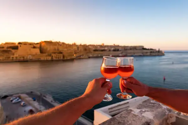 Casal brindando com paisagem de Malta ao fundo