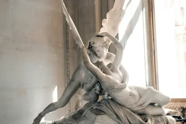 Escultura Psique e Cupido no Museu do Louvre, iluminada pela luz natural da janela.