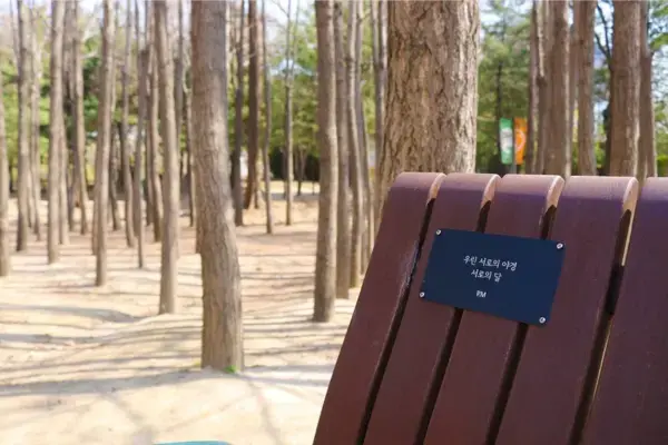 Banco dedicado a RM no Seoul Forest com placa gravada em coreano