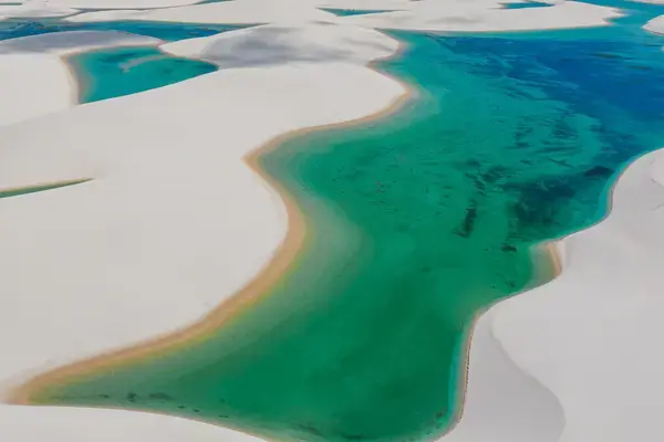 Vista aérea de lagoas azul-esverdeadas entre dunas brancas nos Lençóis Maranhenses.