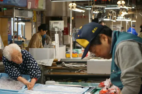 Mulher idosa trabalha em um mercado de peixes no Japão