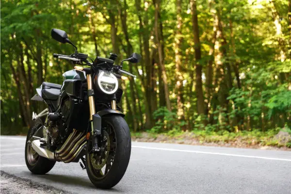 Motocicleta estacionada em estrada cercada por floresta, viagem de moto segura
