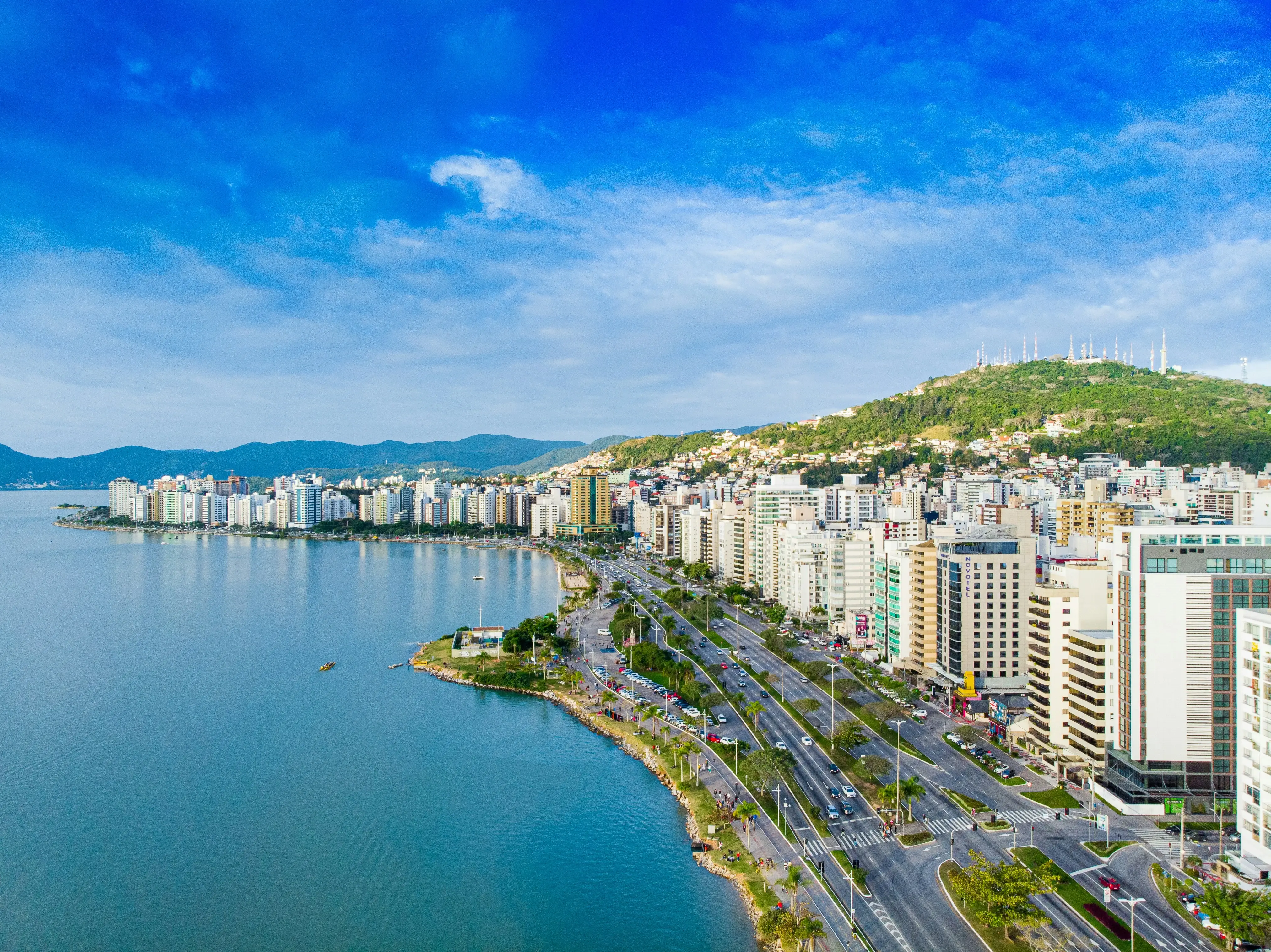 cidade com arranha-céus vendo o mar azul sob o céu azul e branco