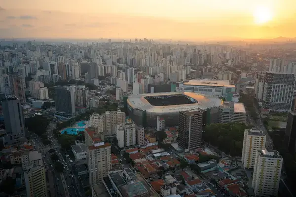 Vista aérea do Allianz Parque ao pôr do sol, cercado por prédios na cidade de São Paulo.