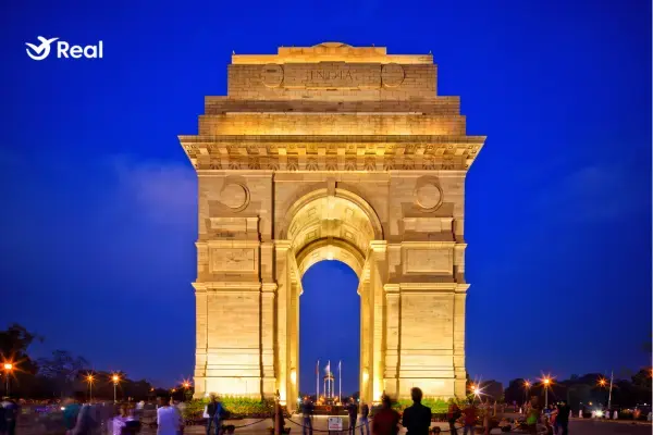 Monumento India Gate iluminado com luzes douradas durante a noite em Nova Delhi.