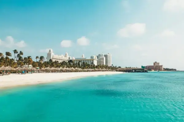 Praia de Aruba com areia branca, mar azul-turquesa e hotéis à beira-mar.
