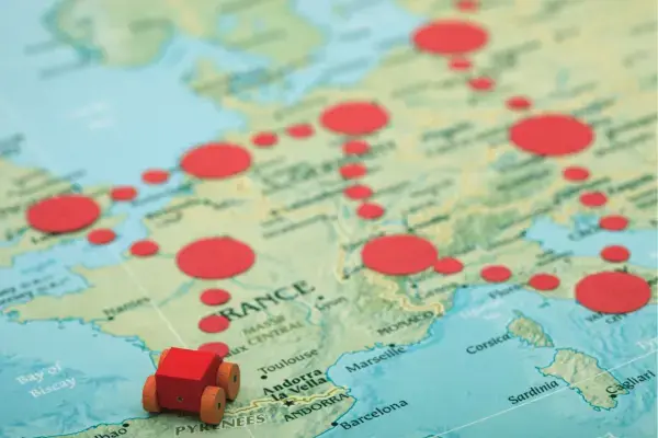 Carrinho vermelho sobre mapa da Europa com pontos de rota marcados.