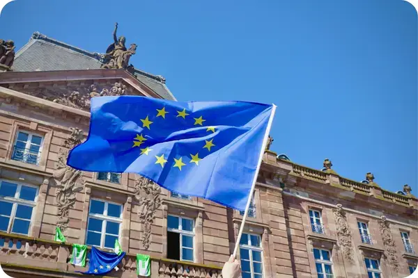 Bandeira da União Europeia tremulando diante de prédio histórico na Europa