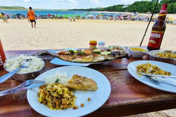 Prato de peixe assado servido à beira da praia em Alter do Chão, com vista para areia clara e rio ao fundo.
