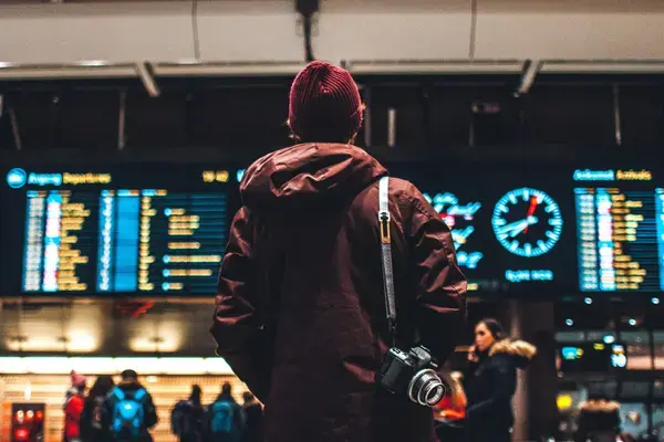 Viajante caminhando com câmera em saguão de aeroporto internacional