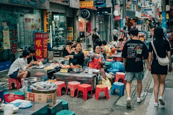 Barracas de comida de rua com banquinhos coloridos em mercado de Busan