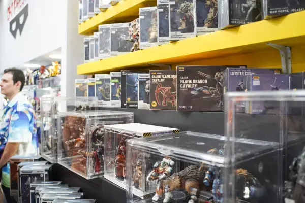 Estande da BGS com prateleiras cheias de action figures e vitrines exibindo colecionáveis detalhados.