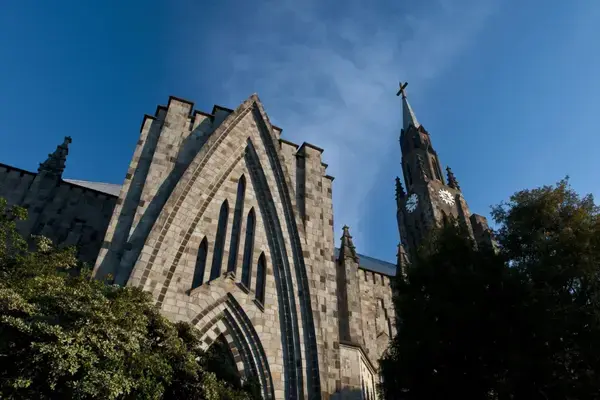 Fachada da Catedral de Pedra em Canela/RS vista de baixo, com torre gótica e céu azul ao fundo