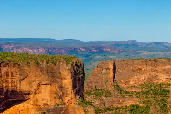 Cânions e paredões de arenito na Chapada dos Guimarães sob céu azul.