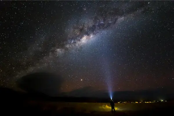Via Láctea sobre o deserto do Atacama com viajante observando o céu noturno