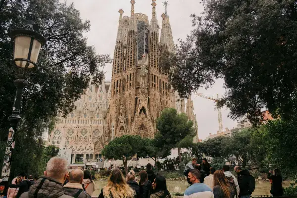 Visitantes em frente à Sagrada Família com vista da basílica refletida no lago.