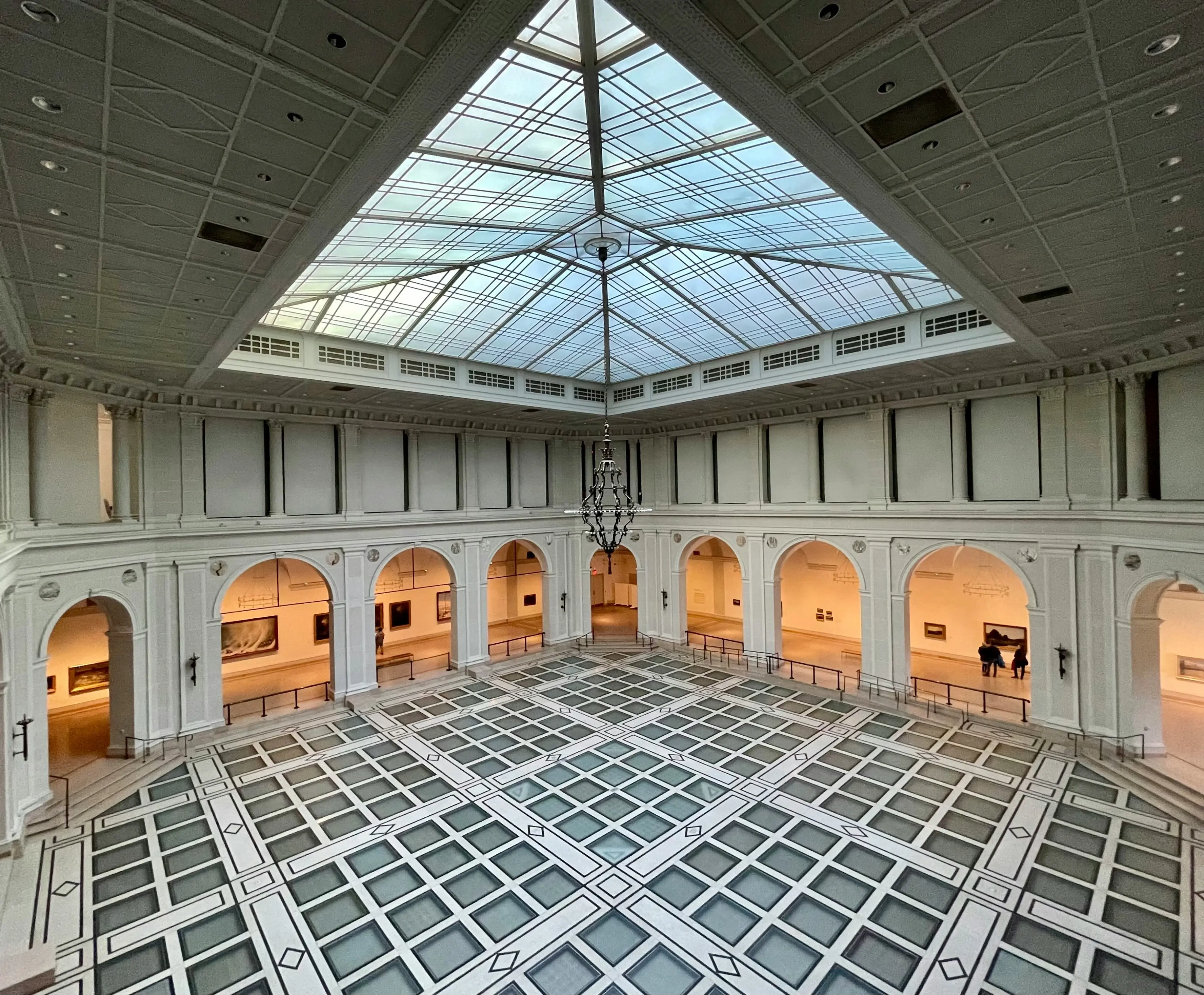 Salão central do Brooklyn Museum com claraboia de vidro e piso geométrico