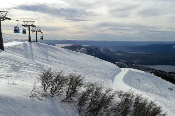Teleférico sobre pistas nevadas do Cerro Catedral em Bariloche com lago Nahuel Huapi ao fundo