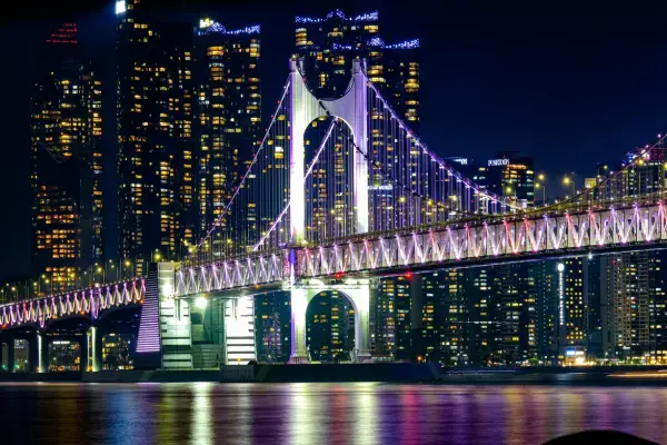 Ponte Gwangan iluminada à noite com os arranha-céus de Busan ao fundo