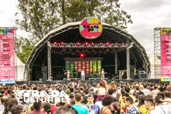 Público lotado em frente ao palco da Virada Cultural de São Paulo com logo do evento ao fundo (Fonte: Divulgação | Virada Cultural)
