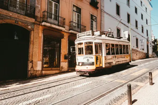 Rua inclinada de Lisboa com bonde amarelo e prédios antigos