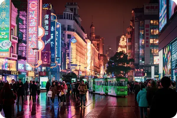 Movimento noturno na rua Nanjing, em Xangai, com letreiros de neon e bondes