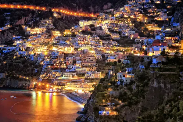 Casas iluminadas de Positano na Costa Amalfitana, Itália, ao anoitecer.