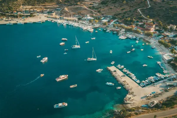 Baía de águas azul-turquesa em Zakynthos, com diversos barcos ancorados próximos à costa e pequenas construções ao redor.