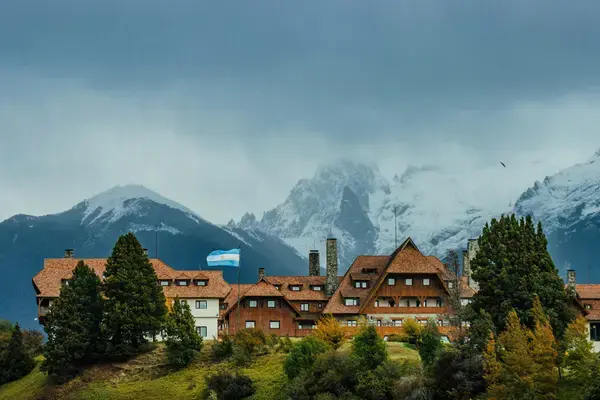 Hotel em Bariloche com montanhas nevadas ao fundo, na Argentina.