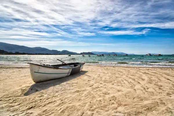 Areia, barco e mar em praia de Florianópolis