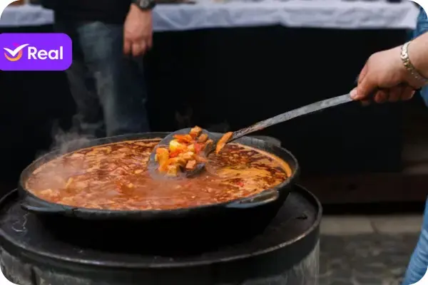 Goulash, panela cheia com uma mao mexendo no caldo.