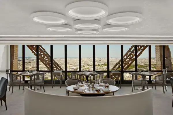 Interior do restaurante Le Jules Verne, localizado na Torre Eiffel, com vista panorâmica de Paris pelas janelas.