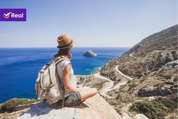 mulher sentada na beirada de uma montanha observando o mar