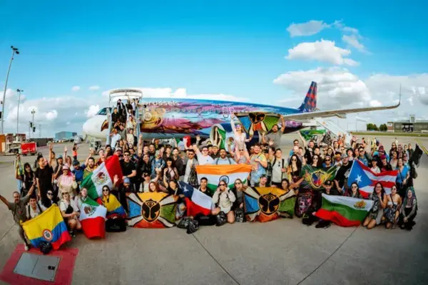 Participantes do Global Journey posando com bandeiras de vários países em frente ao avião temático