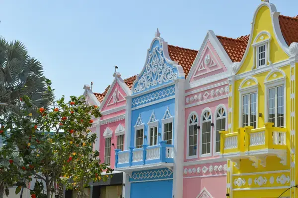 Fachadas de edifícios coloniais holandeses coloridos em amarelo, rosa e azul em Aruba.