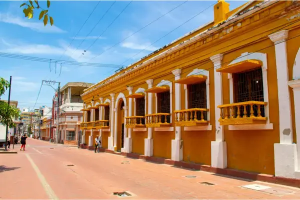 Rua do centro histórico de Santa Marta com casarão colonial amarelo e sacadas brancas