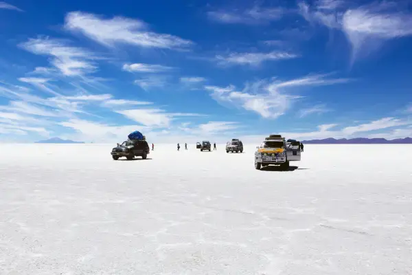 Veículos 4x4 atravessando a superfície branca do Salar de Uyuni na estação seca